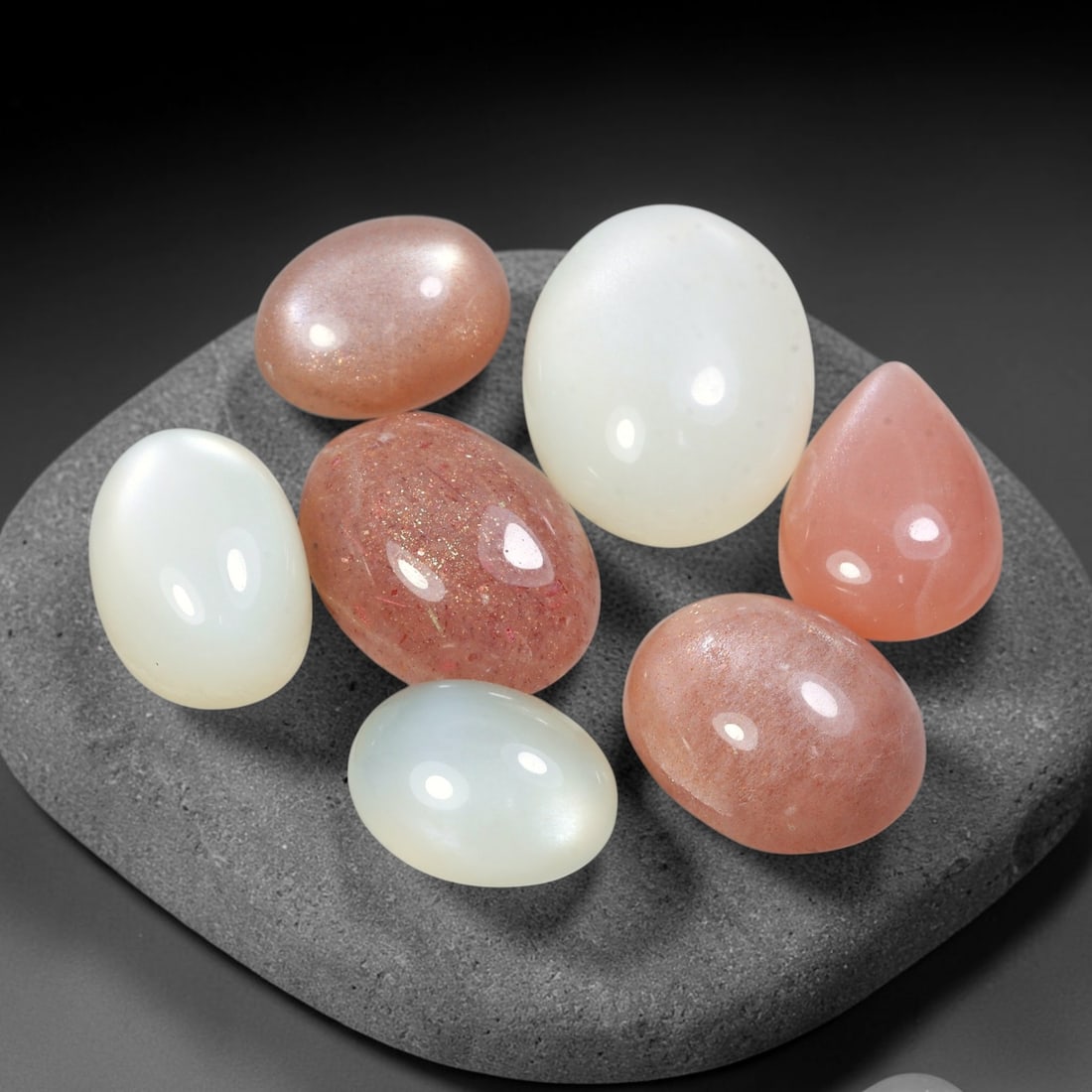 91.86ct Natural Ceylon Moonstone Cabochon Loose Gemstone Parcel Lot, 90EV: This substantial parcel of Ceylon moonstone cabochons showcases soft milky white, warm peach-pink and cool grey-silver tones across smoothly polished oval domed forms. Gentle adularescent sheen drifts