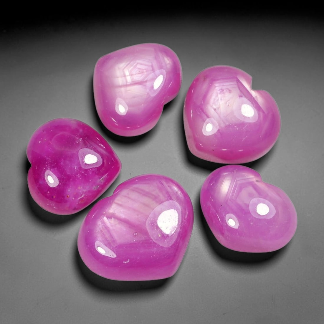 29.26ct Natural Mozambican Ruby Cabochon Loose Gemstone Parcel Lot, 68EV: This distinctive parcel of heart-shaped ruby cabochons displays rich saturated magenta-red colour with visible hexagonal internal growth patterns across smooth polished domed surfaces. Each heart-form