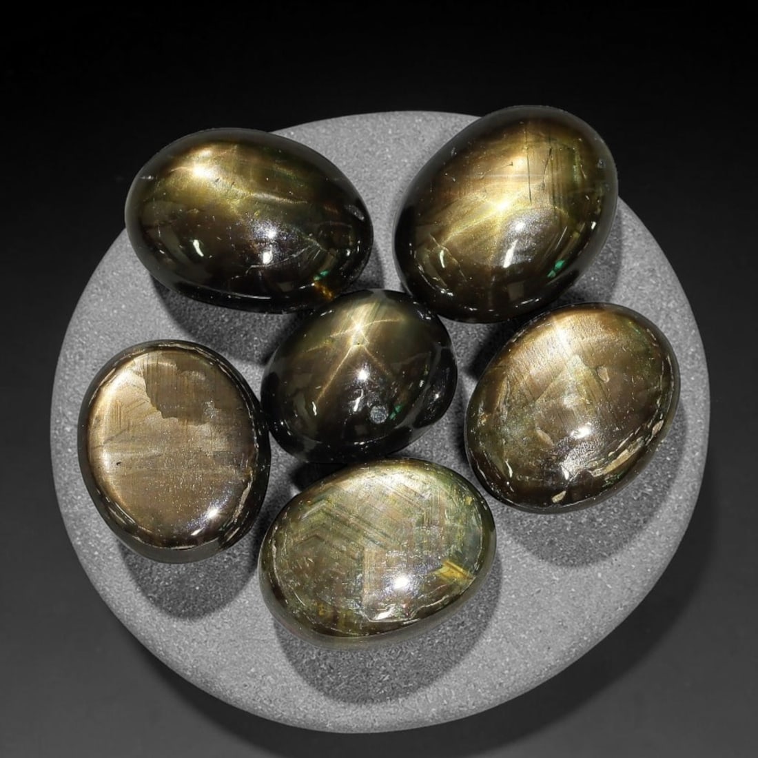 15.39ct Natural Siamese Golden Star Sapphire Cabochon Loose Gemstone Parcel Lot, 76EV: This striking parcel of Siamese golden star sapphire cabochons features deep smoky-golden body tones with sharp well-defined six-rayed asterism across smooth polished oval domed surfaces. Bright metal
