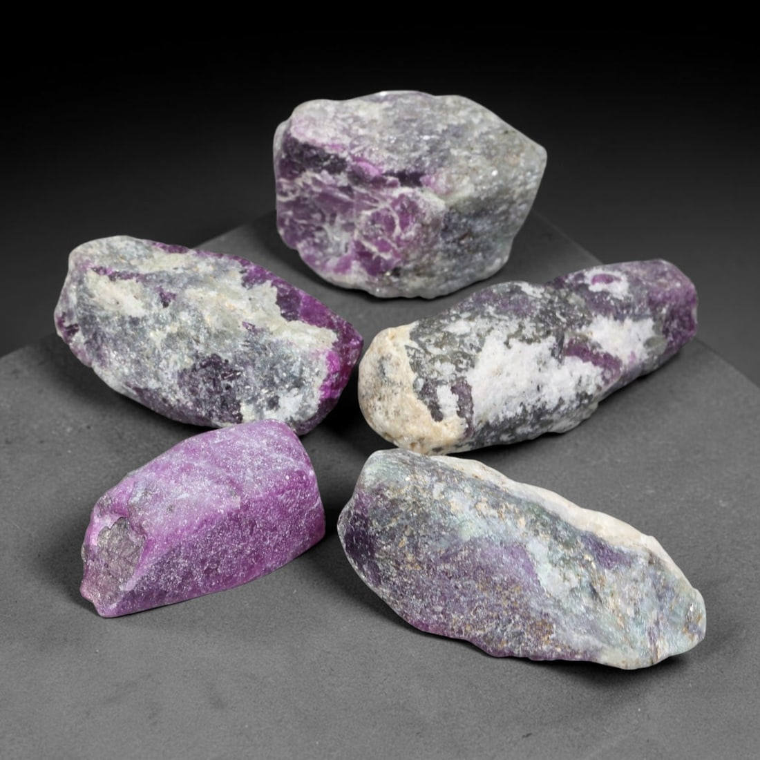 173ct Natural Mauritania Unheated Ruby Rough Parcel Lot, 96EV: This raw parcel of Mauritania ruby rough features vivid magenta-purple crystalline ruby hosted within contrasting pale quartz and mineral matrix. Irregular unpolished specimens display exposed ruby zo