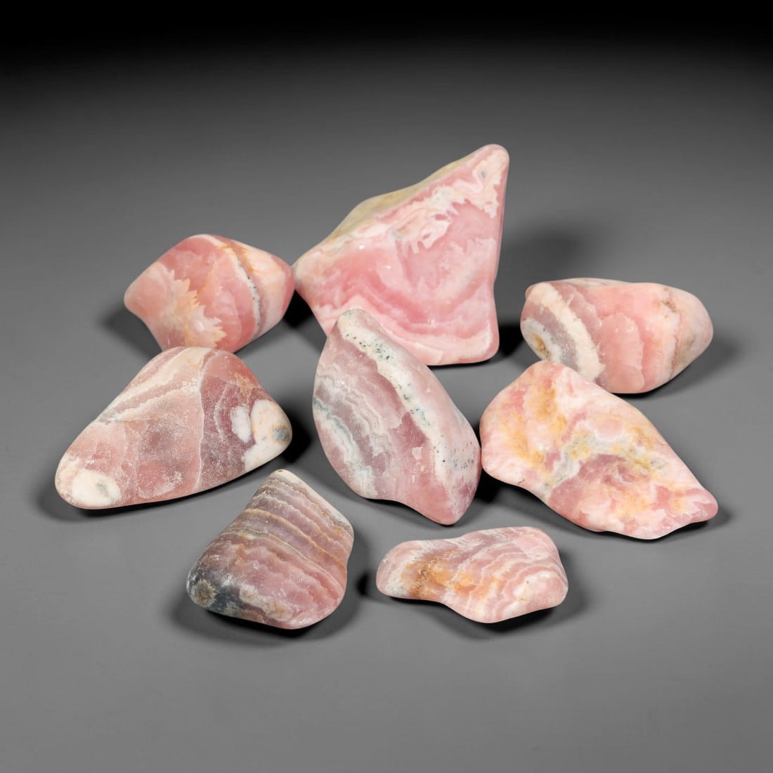 181ct Natural Argentinian Rhodochrosite Tumbled Rough Parcel Lot, 99EV: This beautiful parcel of tumbled rhodochrosite rough showcases striking banded patterning of rich rose-pink, creamy white and subtle earth-toned mineral layers across smooth free-form tumbled surfaces