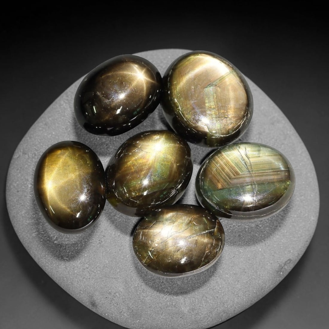 18.55ct Natural Siamese Golden Star Sapphire Cabochon Loose Gemstone Parcel Lot, 74EV: This striking parcel of Siamese golden star sapphire cabochons features deep smoky-golden body tones with sharp well-defined six-rayed asterism across smooth polished oval domed surfaces. Bright metal