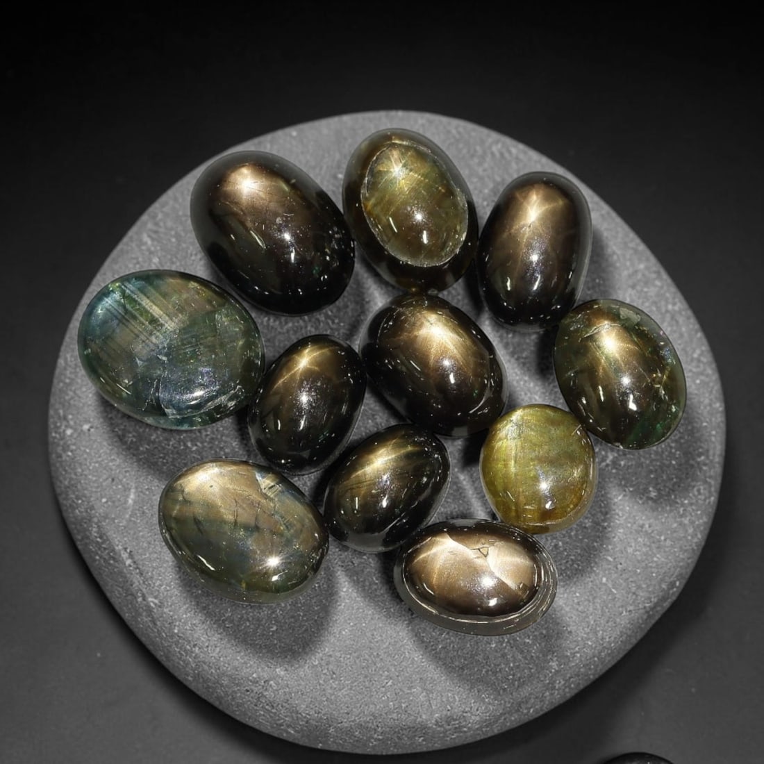 14.36ct Natural Siamese Golden Star Sapphire Cabochon Loose Gemstone Parcel Lot, 72EV: This striking parcel of Siamese golden star sapphire cabochons features deep smoky-golden body tones with sharp well-defined six-rayed asterism across smooth polished oval domed surfaces. Bright metal