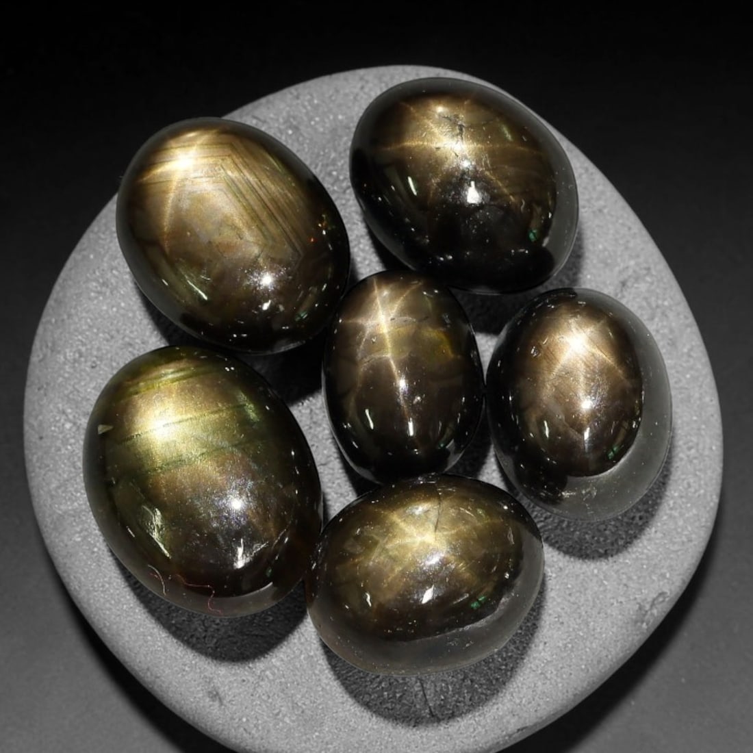 17.38ct Natural Siamese Golden Star Sapphire Cabochon Loose Gemstone Parcel Lot, 78EV: This striking parcel of Siamese golden star sapphire cabochons features deep smoky-golden body tones with sharp well-defined six-rayed asterism across smooth polished oval domed surfaces. Bright metal
