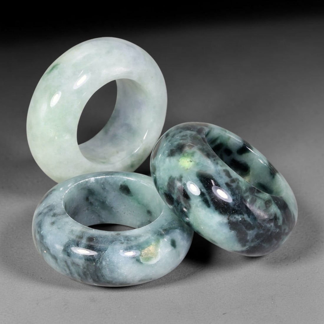 Burmese Type-A Jadeite Jade Thumb Rings Chinese Archer Set, 29EW: Crafted from natural Burmese Type-A jadeite jade, this set of three archer's thumb rings displays varied natural stone tones including pale celadon, deep bluish-green, with scattered russet and dark m