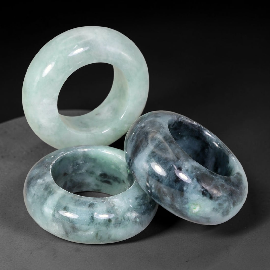 Burmese Type-A Jadeite Jade Thumb Rings Chinese Archer Set, 33EW: Crafted from natural Burmese Type-A jadeite jade, this set of three archer's thumb rings displays varied natural stone tones including pale celadon, deep bluish-green, with scattered russet and dark m