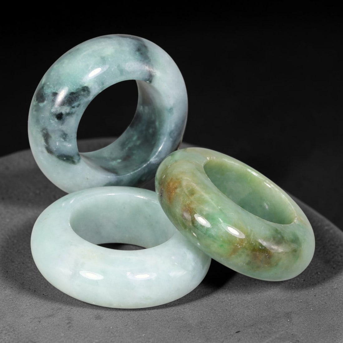 Burmese Type-A Jadeite Jade Thumb Rings Chinese Archer Set, 34EW: Crafted from natural Burmese Type-A jadeite jade, this set of three archer's thumb rings displays varied natural stone tones including pale celadon, deep bluish-green, with scattered russet and dark m
