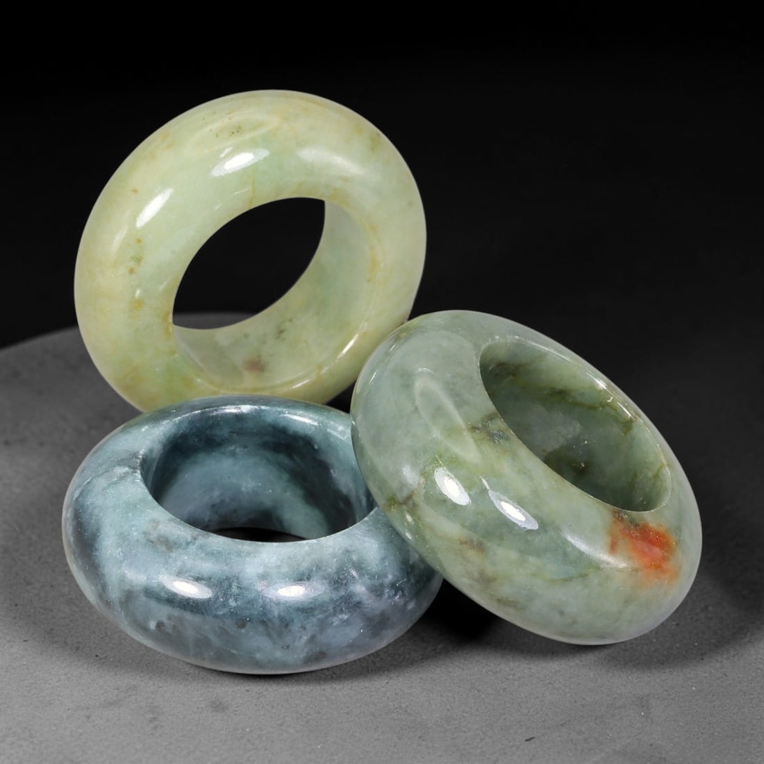 Burmese Type-A Jadeite Jade Thumb Rings Chinese Archer Set, 32EW: Crafted from natural Burmese Type-A jadeite jade, this set of three archer's thumb rings displays varied natural stone tones including pale celadon, deep bluish-green, with scattered russet and dark m