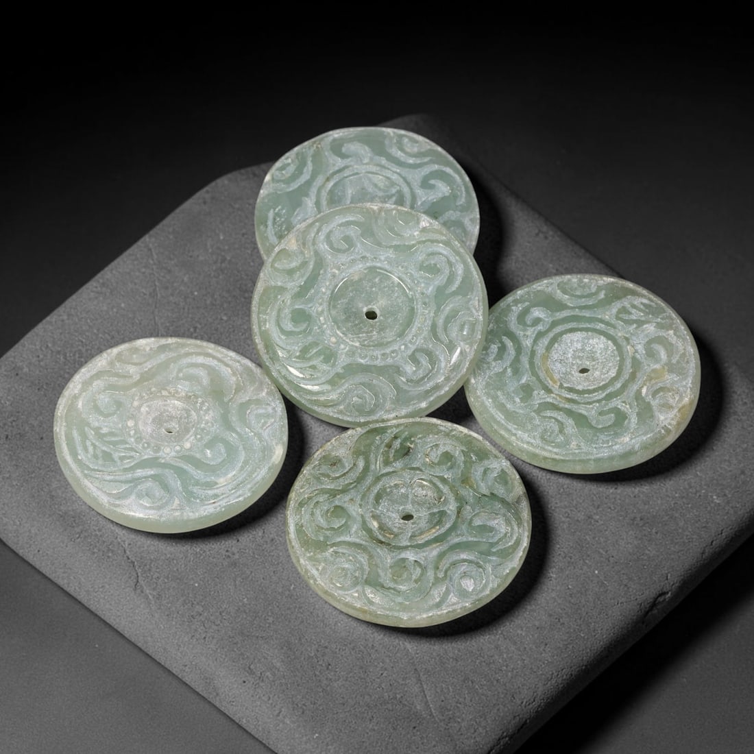 Vintage Jadeite Jade Carved Disc Pendants Chinese Ornament Set, 22EW: Crafted from vintage jadeite jade, this set of five circular disc pendants showcases open stylized scroll-work carving across each face, with central suspension holes for wear. The group exhibits vari