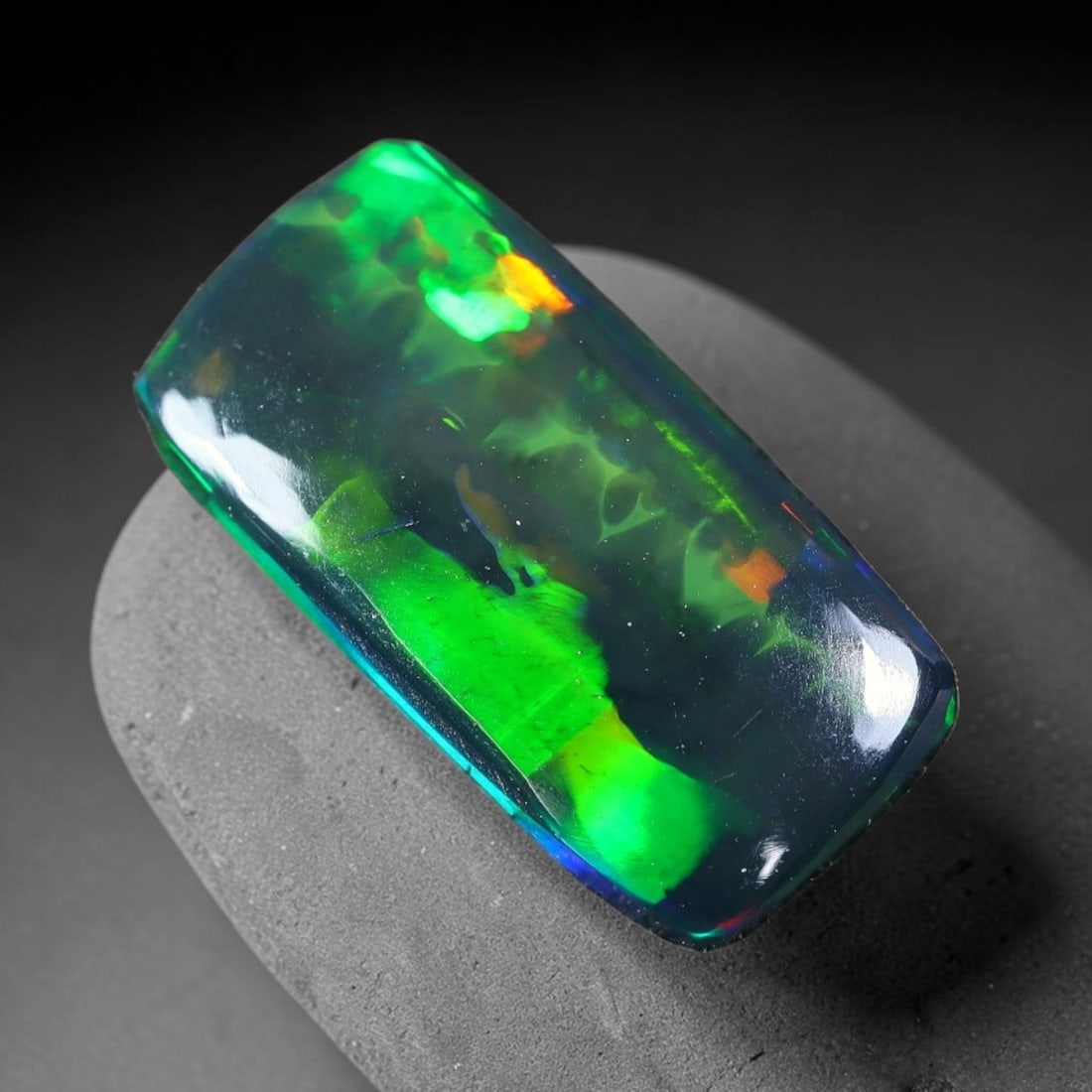 1.78ct Natural Ethiopian Welo Black Smoked Opal Cabochon Loose Gemstone, 59FX: This fully polished Ethiopian Welo opal features a dark smoked base with vivid, sweeping play-of-color shifting across its glossy dome surface, measured at 14x7x2mm. The black smoke treatment deepens 