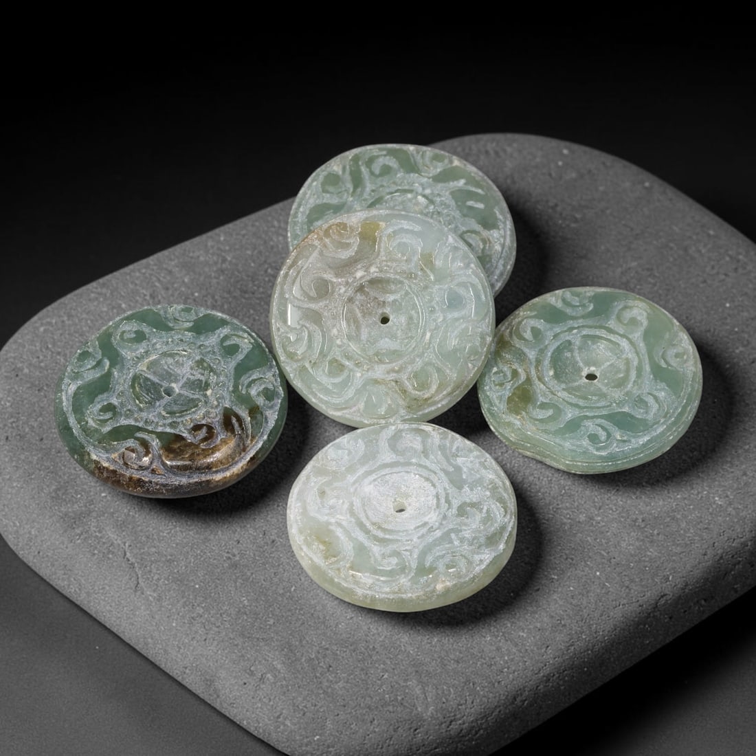 Vintage Jadeite Jade Carved Disc Pendants Chinese Ornament Set, 23EW: Crafted from vintage jadeite jade, this set of five circular disc pendants showcases open stylized scroll-work carving across each face, with central suspension holes for wear. The group exhibits vari