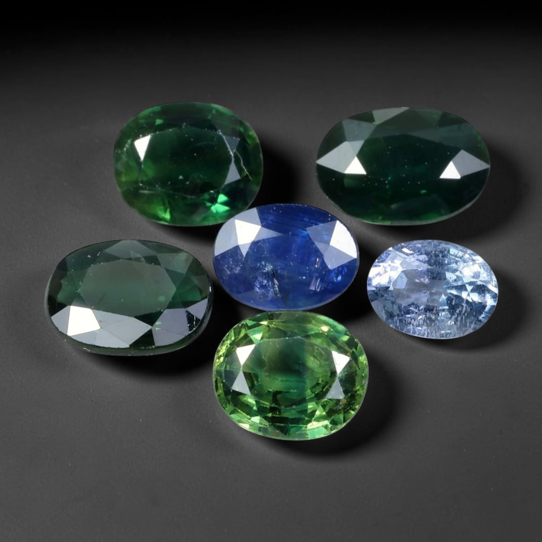 7.04ct Natural Australian Multitone Sapphire Loose Gemstone Parcel Lot, 50EV: This varied parcel of Australian sapphires presents a striking spectrum of deep forest green, vivid teal-green, rich royal blue, and soft pale blue tones. Each oval-faceted gem delivers crisp light re