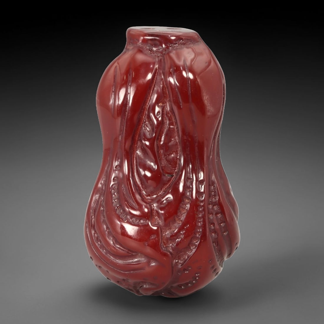 A Chinese Amber-Resin Cabbage Pendant, 38FC: Molded from translucent amber-colored resin with a deep red tone and high-gloss surface, the pendant is carved in the form of a cabbage with layered, curling leaves gathered into a compact, vertical c