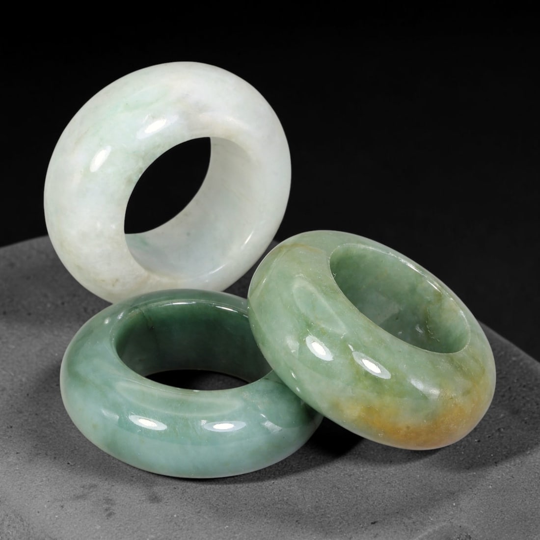 Burmese Type-A Jadeite Jade Thumb Rings Chinese Archer Set, 30EW: Crafted from natural Burmese Type-A jadeite jade, this set of three archer's thumb rings displays varied natural stone tones including pale celadon, deep bluish-green, with scattered russet and dark m