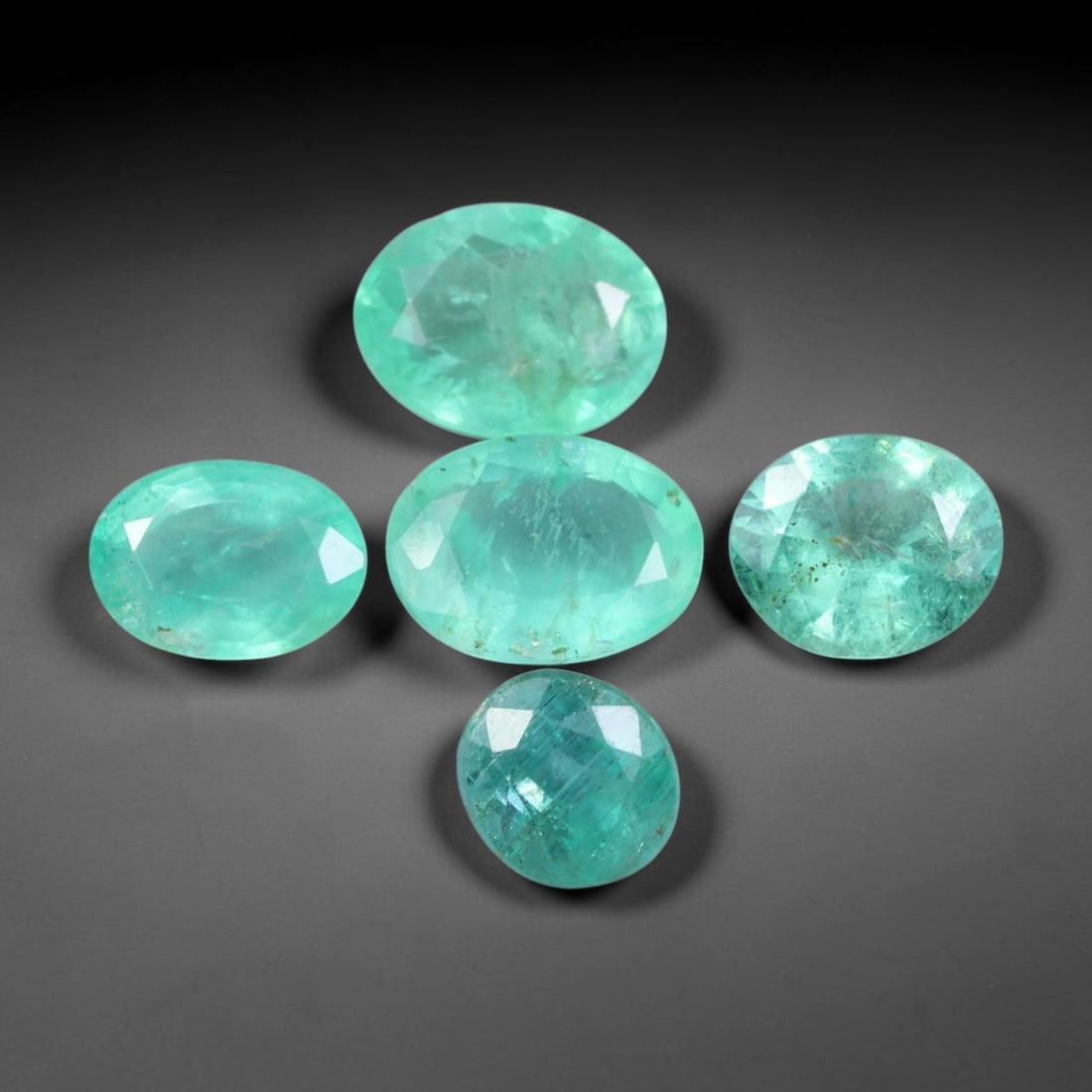 4.67ct Natural Zambian Vivid Green Emerald Loose Gemstone Parcel Lot, 65EV: This curated parcel of faceted emeralds delivers rich vivid green tones with soft internal glow, displaying natural textural details across well-proportioned oval cuts. Light passes through each gem t