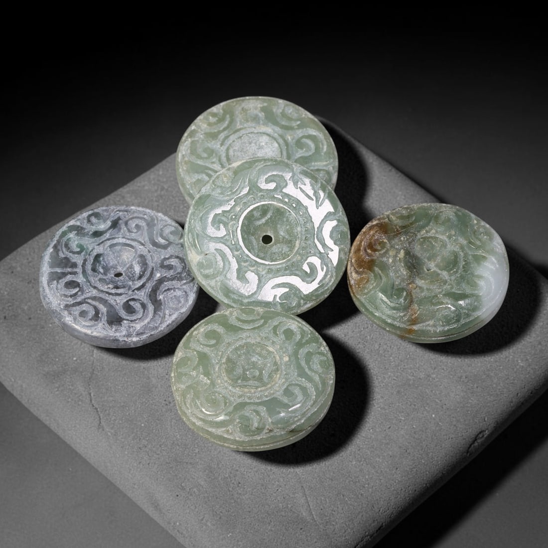 Vintage Jadeite Jade Carved Disc Pendants Chinese Ornament Set, 24EW: Crafted from vintage jadeite jade, this set of five circular disc pendants showcases open stylized scroll-work carving across each face, with central suspension holes for wear. The group exhibits vari