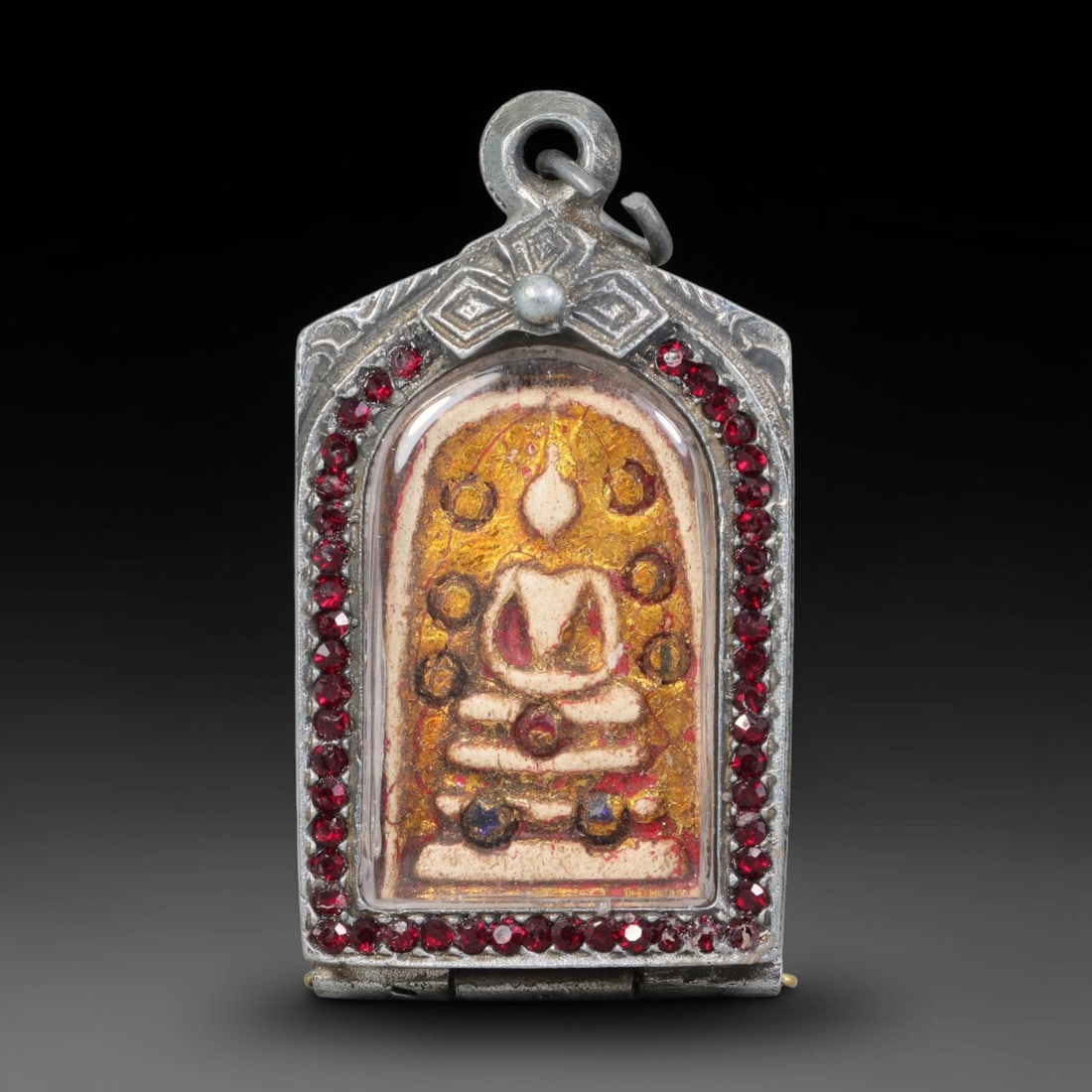 Thai Buddhist Folk Tradition Enclosed Amulet Pendant with Decorative Metal Casing, 17AH: This Thai sacred amulet is housed within an ornate hinged metal protective casing fitted with a top loop for wear as a pendant. The casing features intricate embossed surface detailing and a continuou