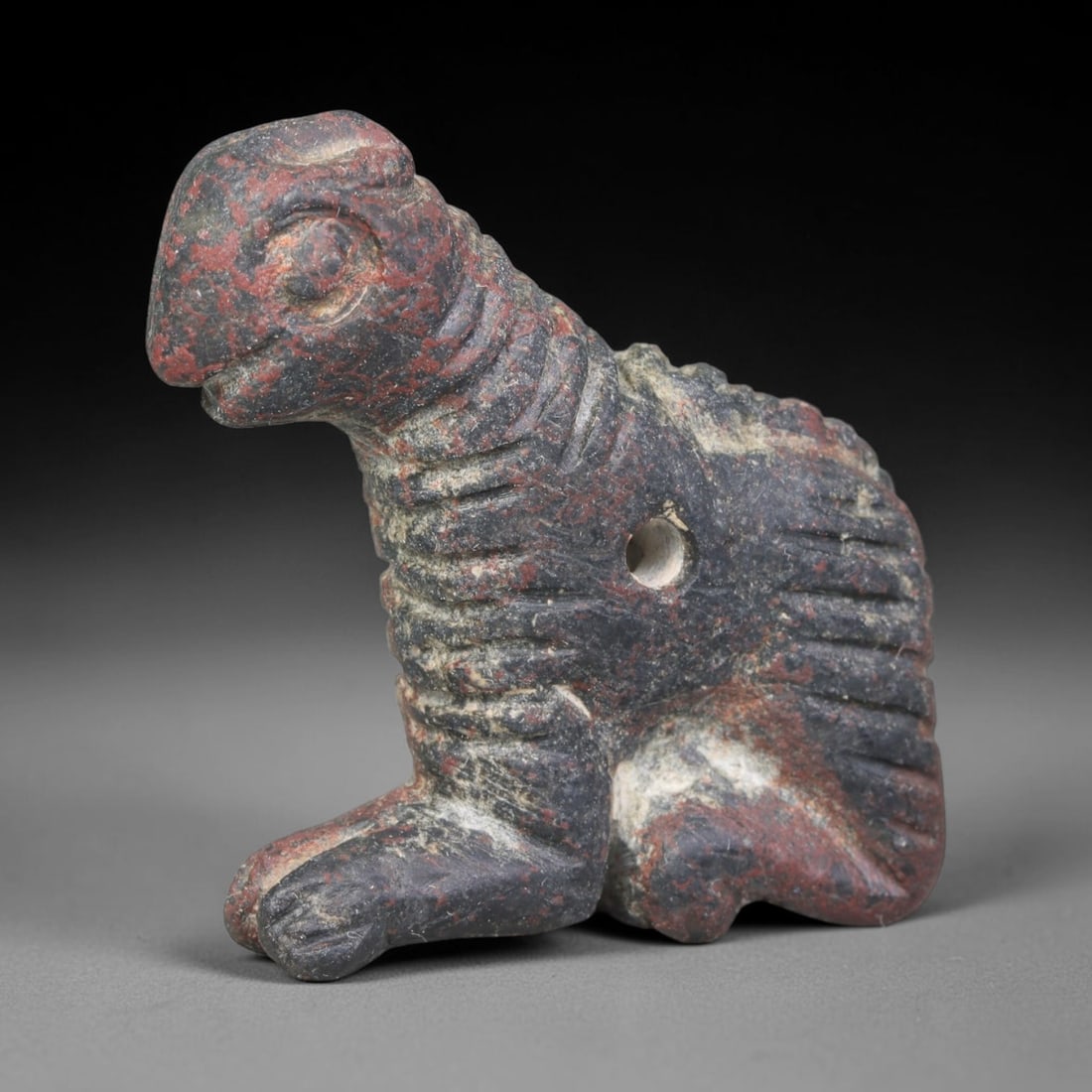 Ancient Bactrian Dark Stone Mythical Reptilian Guardian Amulet (c.200-200 BCE), 6ER: Hand-carved from dark mottled metamorphic stone originating within ancient Bactria, Central Asia. Rendered as a seated mythical reptilian zoomorphic guardian figure with defined linear incisions artic