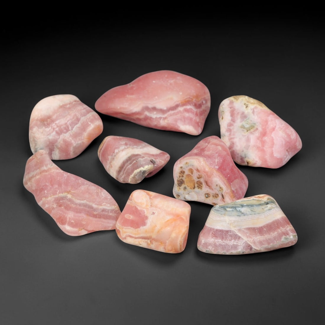 197ct Natural Argentinian Rhodochrosite Tumbled Rough Parcel Lot, 98EV: This beautiful parcel of tumbled rhodochrosite rough showcases striking banded patterning of rich rose-pink, creamy white and subtle earth-toned mineral layers across smooth free-form tumbled surfaces