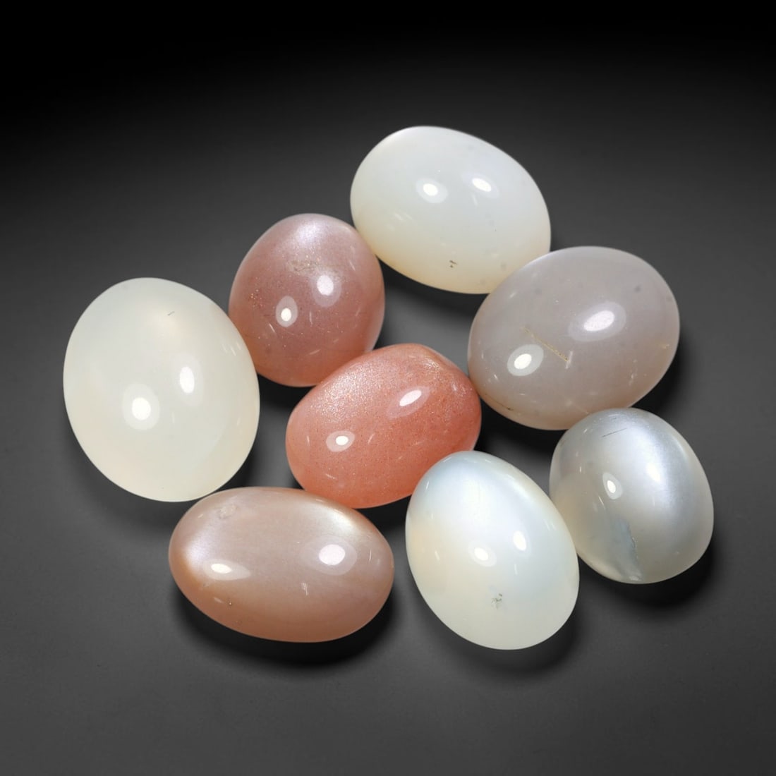 80.35ct Natural Ceylon Moonstone Cabochon Loose Gemstone Parcel Lot, 89EV: This substantial parcel of Ceylon moonstone cabochons showcases soft milky white, warm peach-pink and cool grey-silver tones across smoothly polished oval domed forms. Gentle adularescent sheen drifts
