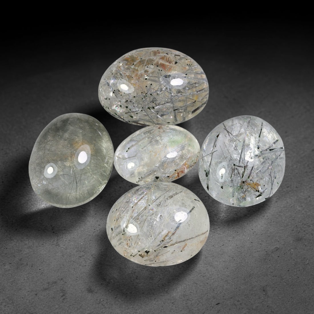 198.05ct Natural Brazilian Rutile Quartz Cabochon Parcel Lot, 55EW: This polished parcel of oval cabochons features clear transparent quartz host densely interspersed with fine metallic black rutile needle inclusions. Each domed high-gloss cabochon displays distinct i