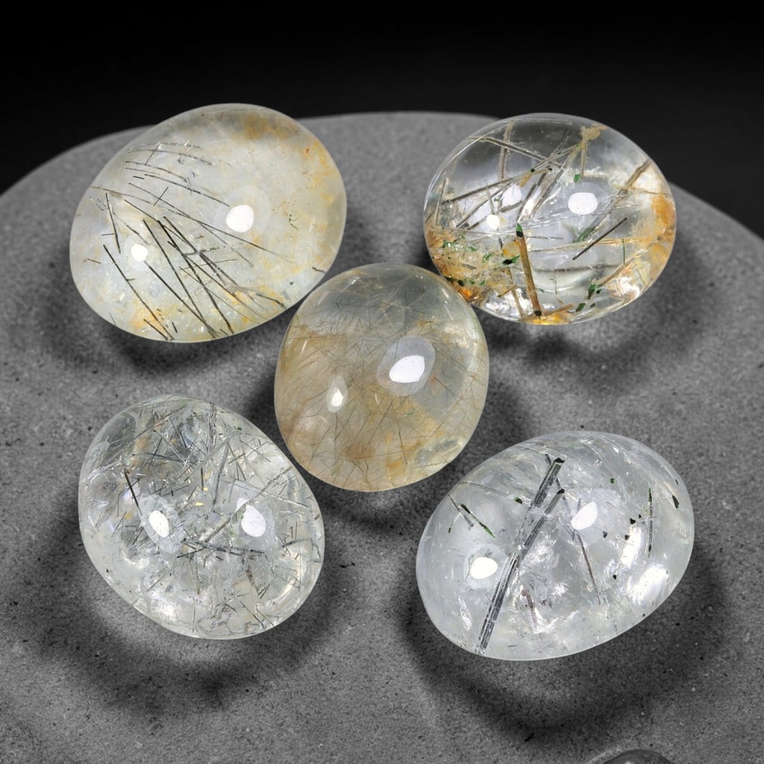 141.04ct Natural Brazilian Rutile Quartz Cabochon Parcel Lot, 56EW: This polished parcel of oval cabochons features clear transparent quartz host densely interspersed with fine metallic black rutile needle inclusions. Each domed high-gloss cabochon displays distinct i