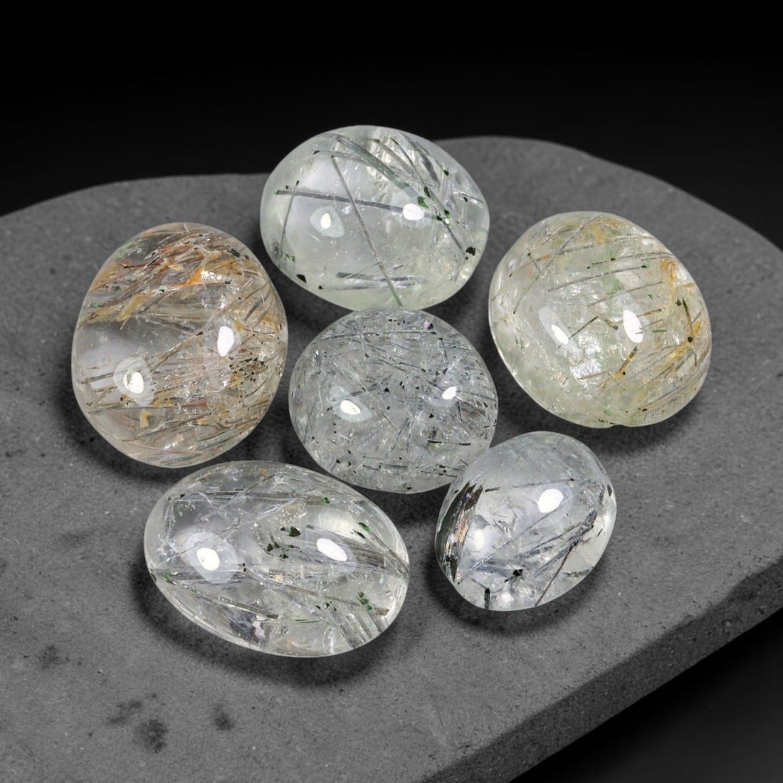 119.97ct Natural Brazilian Rutile Quartz Cabochon Parcel Lot, 57EW: This polished parcel of oval cabochons features clear transparent quartz host densely interspersed with fine metallic black rutile needle inclusions. Each domed high-gloss cabochon displays distinct i
