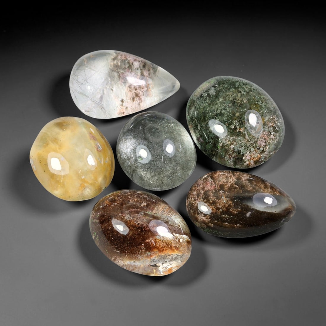 155.66ct Natural Brazilian Phantom Quartz Cabochon Parcel Lot, 66EW: This polished cabochon parcel of natural phantom quartz features transparent clear quartz host stone enclosing intricate internal phantom mineral deposits. Each oval cabochon displays unique scenic in