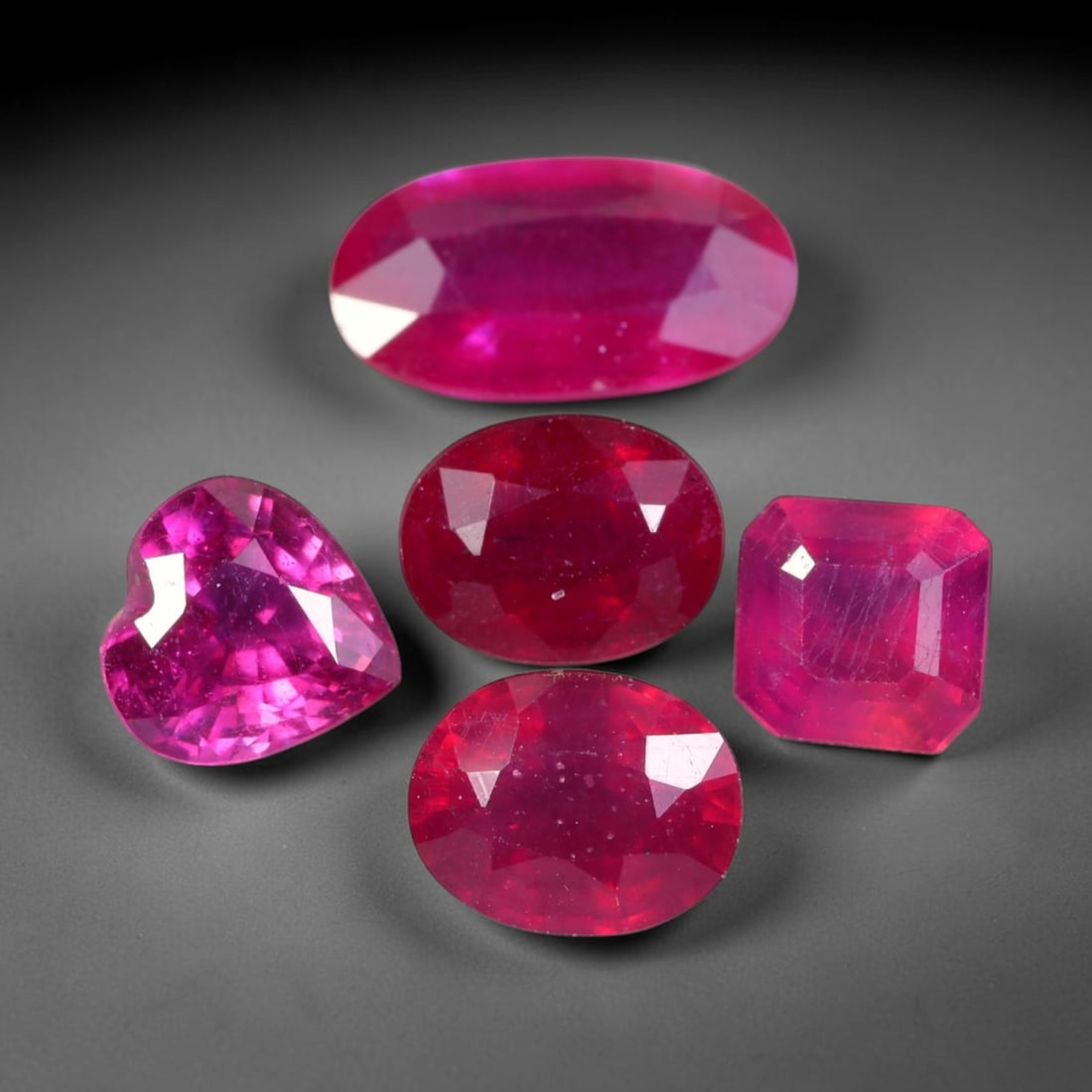 9.54ct Natural Mozambican Ruby Faceted Parcel Lot, 38EW: This faceted gemstone lot features multiple mixed-shape cut rubies displaying rich saturated crimson to vivid pink-red colour tones across oval, heart and square modified faceted forms. Each stone is 