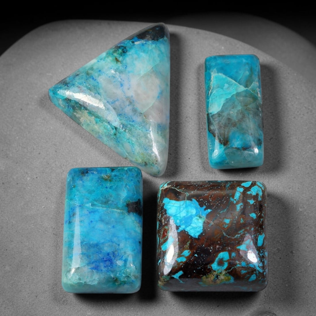 90.34ct Natural Peruvian Chrysocolla Cabochon Parcel Lot, 49EX: This polished cabochon parcel presents finished chrysocolla cabochons in mixed free-form, rectangular and square silhouettes. Bright turquoise-blue and teal chrysocolla blends with quartz host matrix,