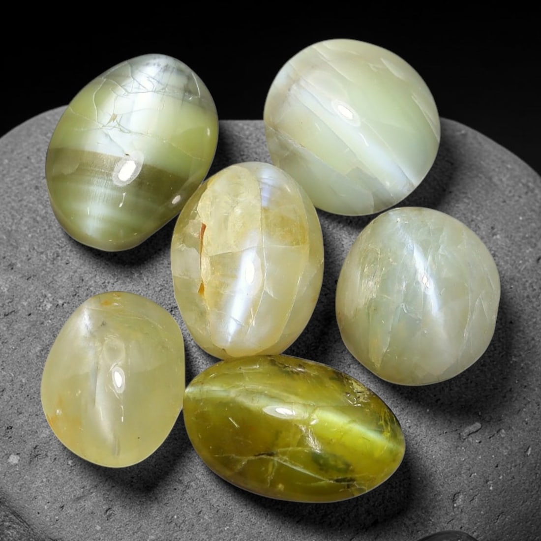11.85ct Natural Ceylon Chrysoberyl Cat's Eye Cabochon Parcel Lot, 24EX: This polished cabochon parcel features oval and round cabochon chrysoberyl cat's eye from Sri Lanka. Smooth domed surfaces display sharp, well-defined chatoyant cat's-eye band across soft yellowish-gr