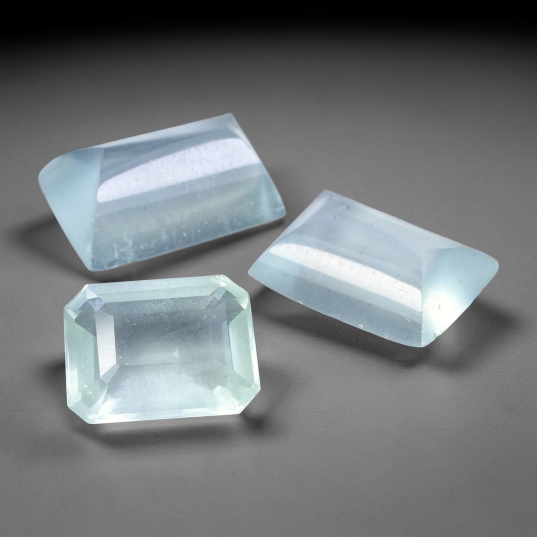 7.68ct Natural Brazilian Aquamarine Mixed Cut Parcel Lot, 23EX: This parcel combines one faceted emerald-cut aquamarine paired with two polished cabochon aquamarine pieces, exhibiting soft pale sky-blue colouration across transparent to semi-transparent gem materi