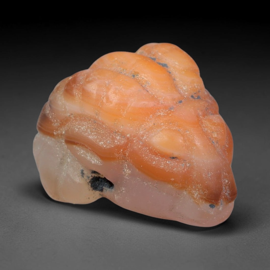 Ancient Sasanian Persian Agate Ram Head Amulet Bead (224-651 CE), 26EC: This antique ram head amulet bead carved from natural agate originates from the Sasanian Persian Empire. Ram motifs stood as powerful symbols of fertility, strength and divine protection within ancien