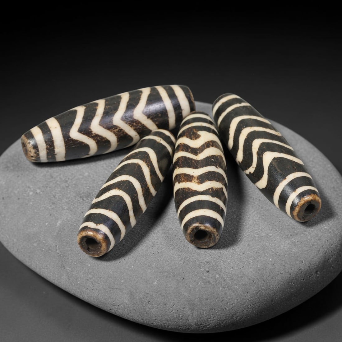 Antique Indo-Himalayan Pumtek Wood Elongated Etched Beads, 97ET: A collectible group of four antique Indo-Himalayan pumtek wood elongated beads, decorated with traditional etched zig-zag symbolic motifs. Each bead bears rich accumulated patina, soft surface wear, a