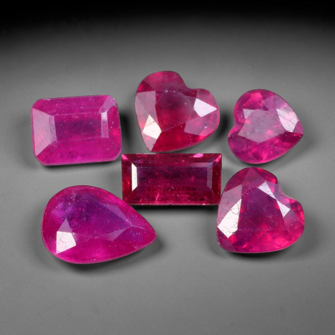 8.00ct Natural Mozambican Ruby Faceted Parcel Lot, 42EW: This faceted gemstone lot features multiple mixed-shape cut rubies displaying rich saturated crimson to vivid pink-red colour tones across oval, heart and square modified faceted forms. Each stone is 