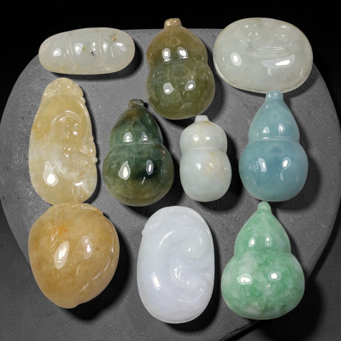 235.83ct Natural Burmese Type A Jadeite Jade Carving Pendant Parcel Lot, 98EX: This parcel lot consists of hand-carved Type A jadeite pendants displaying varied natural colour tones including deep forest green, soft pale green, and warm yellow-gold hues. Each piece finished with