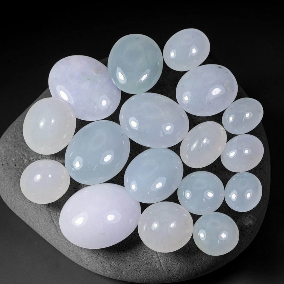 59.53ct Natural Burmese Type A Lavender Jadeite Jade Cabochon Parcel Lot, 40EX: This polished cabochon parcel features oval and round cabochon Type A jadeite jade displaying soft lavender-lilac body tones across the set. Smooth high-gloss domed surfaces showcase gentle colour var