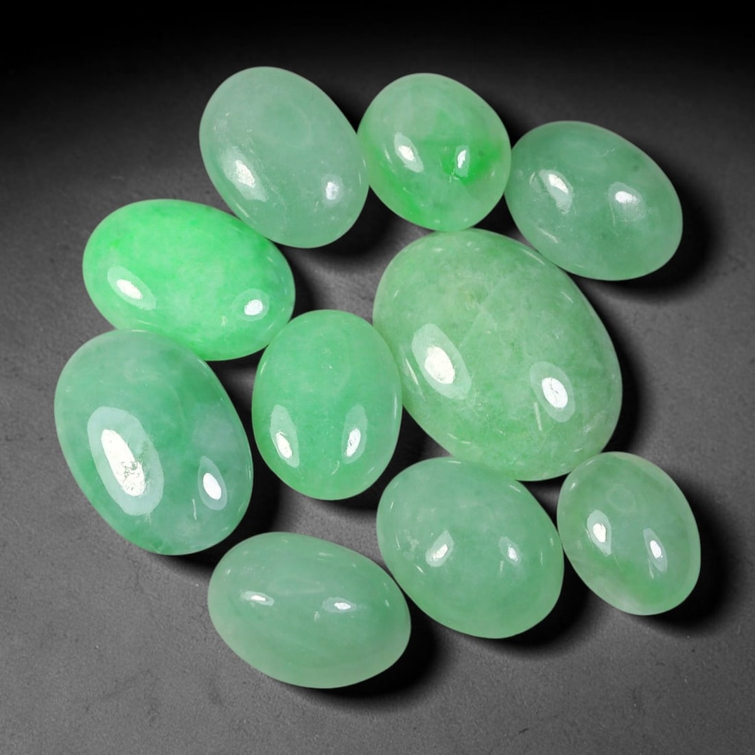 36.43ct Natural Burmese Type A Jadeite Jade Cabochon Parcel Lot, 43EX: This oval cabochon parcel consists of polished Type A jadeite cabochons showing soft pastel to medium lively green colour shades across smooth domed surfaces. Glossy polished finishes reveal natural i