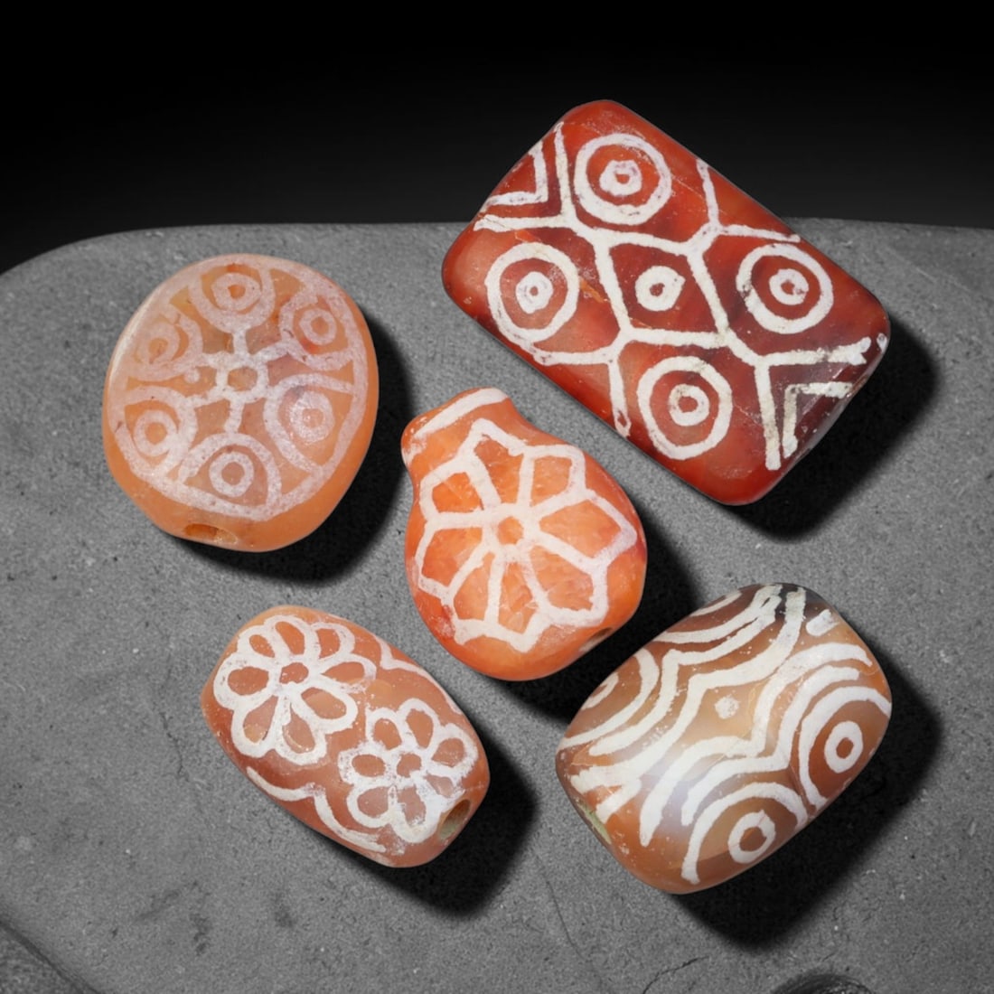 Ancient Sino-Himalayan Region Etched Carnelian Beads Parcel Lot, 2EY: Group of ancient etched carnelian beads originating from the Sino-Himalayan cultural sphere, displaying classic alkali-etch decorative motifs across translucent carnelian bodies. Each bead exhibits hi