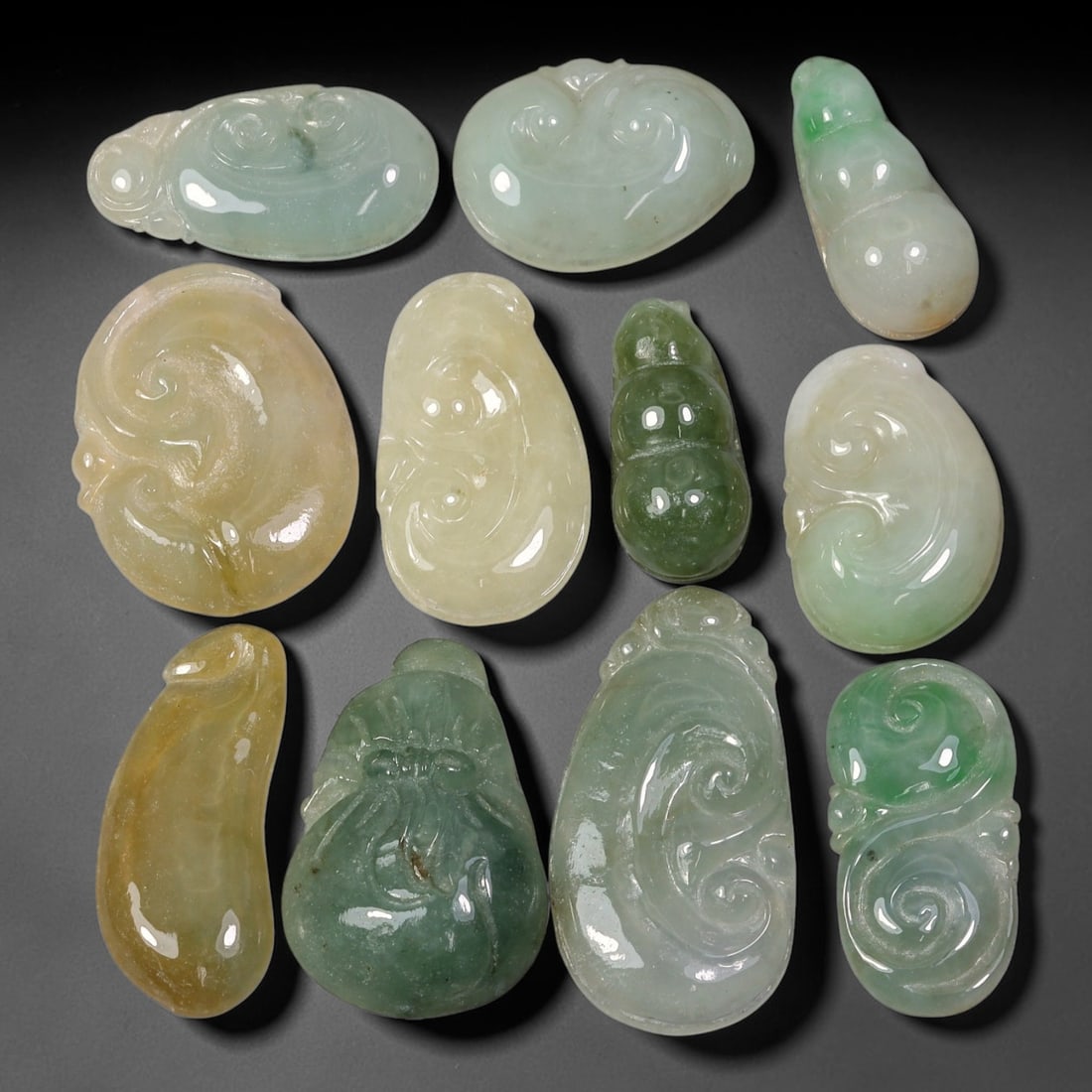 150.72ct Natural Burmese Type A Jadeite Jade Carving Pendant Parcel Lot, 97EX: This parcel lot consists of hand-carved Type A jadeite pendants displaying varied natural colour tones including deep forest green, soft pale green, and warm yellow-gold hues. Each piece finished with