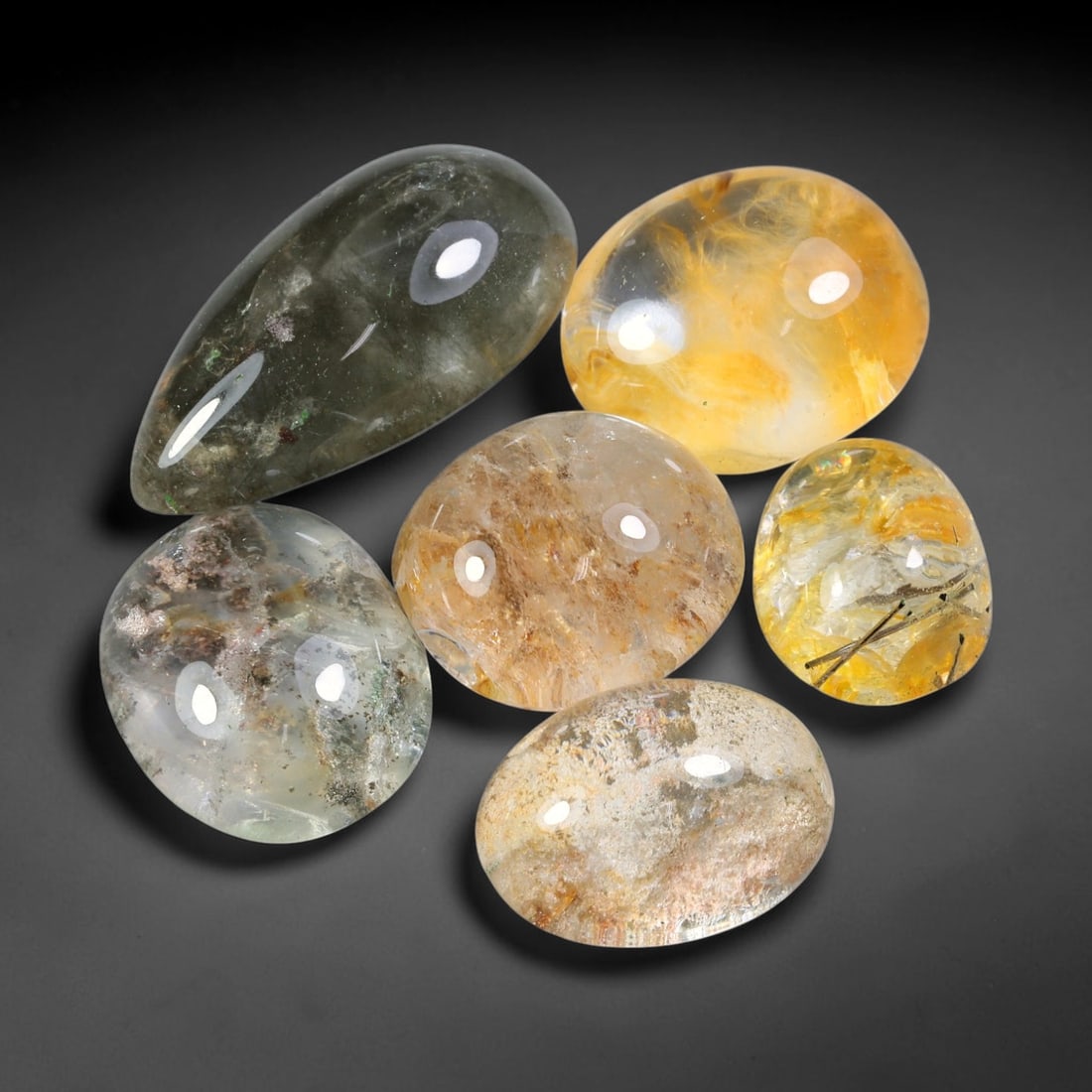 212.20ct Natural Brazilian Phantom Quartz Cabochon Parcel Lot, 63EW: This polished cabochon parcel of natural phantom quartz features transparent clear quartz host stone enclosing intricate internal phantom mineral deposits. Each oval cabochon displays unique scenic in