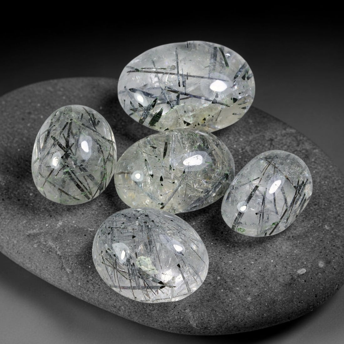 153.24ct Natural Brazilian Rutile Quartz Cabochon Parcel Lot, 53EW: This polished parcel of oval cabochons features clear transparent quartz host densely interspersed with fine metallic black rutile needle inclusions. Each domed high-gloss cabochon displays distinct i