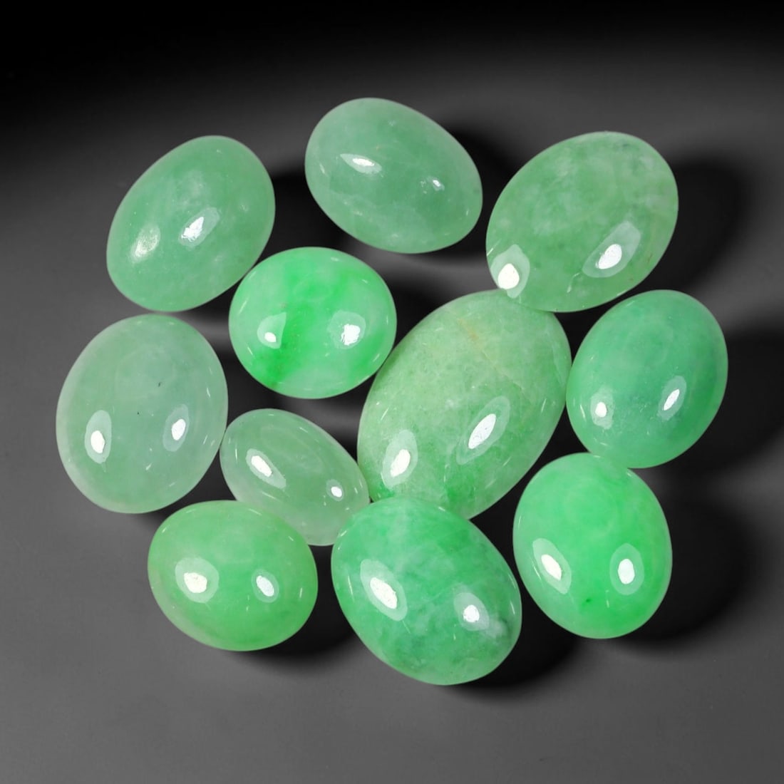 31.93ct Natural Burmese Type A Jadeite Jade Cabochon Parcel Lot, 46EX: This oval cabochon parcel consists of polished Type A jadeite cabochons showing soft pastel to medium lively green colour shades across smooth domed surfaces. Glossy polished finishes reveal natural i
