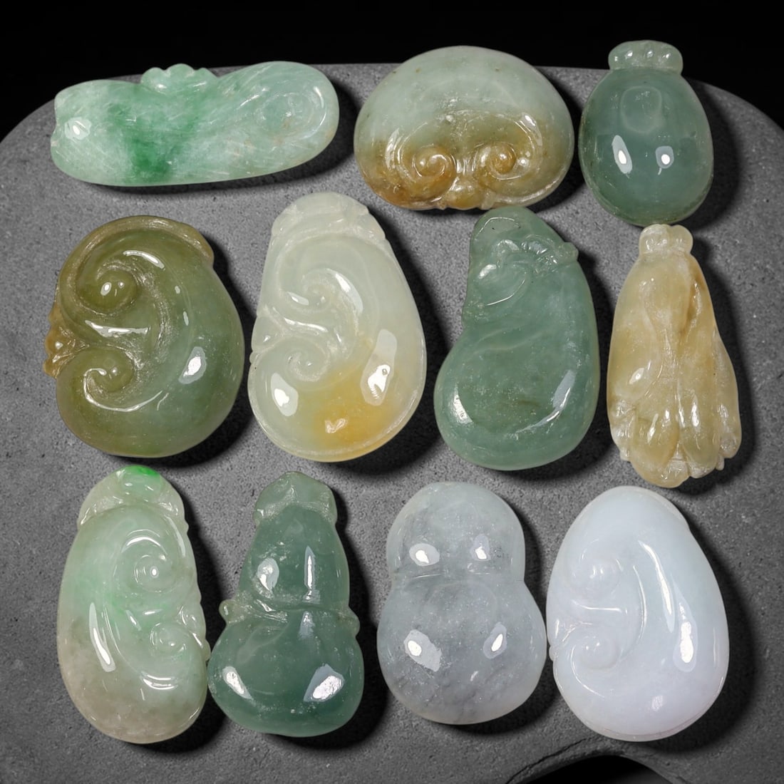 196.62ct Natural Burmese Type A Jadeite Jade Carving Pendant Parcel Lot, 99EX: This parcel lot consists of hand-carved Type A jadeite pendants displaying varied natural colour tones including deep forest green, soft pale green, and warm yellow-gold hues. Each piece finished with
