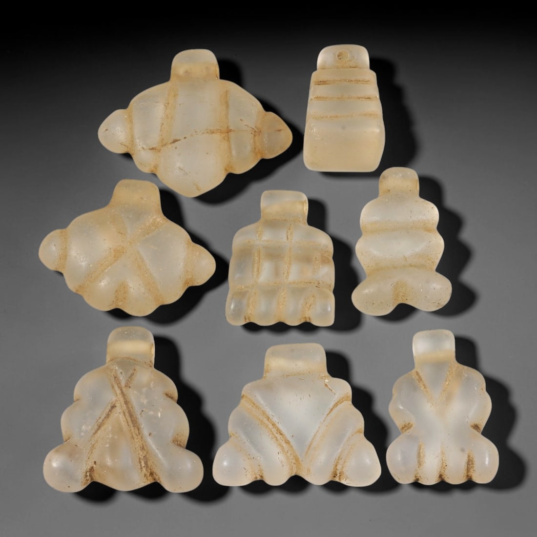 Ancient Medieval Coptic Christian Egyptian Rock Crystal Amulets Parcel Lot, 16EY: Collection of rock-crystal talismans originating from Medieval Coptic Egyptian cultural context, each formed with integral suspension lugs for wear. The group displays carved surface detailing, consis