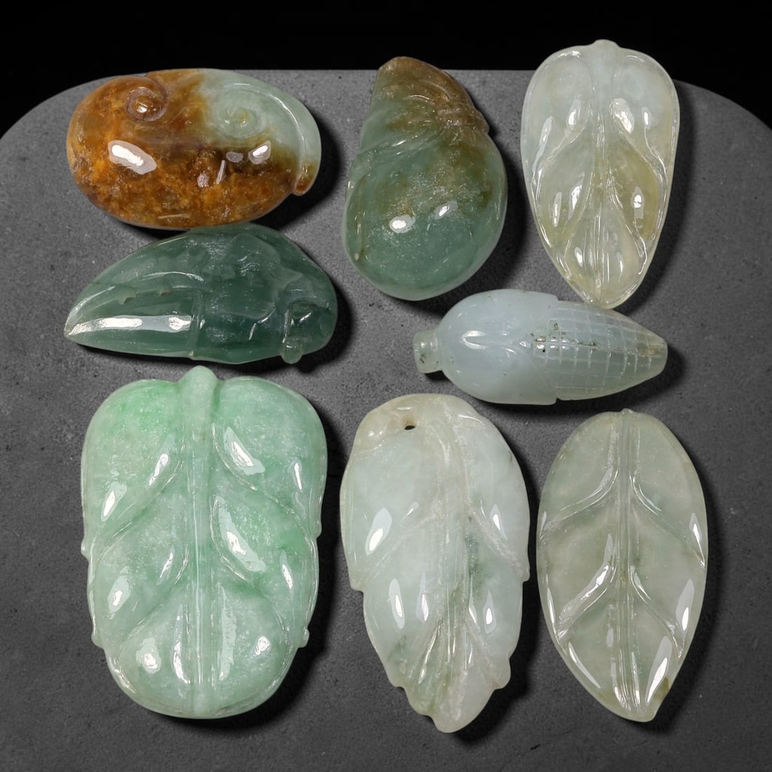198.47ct Natural Burmese Type A Jadeite Jade Carving Pendant Parcel Lot, 96EX: This parcel lot consists of hand-carved Type A jadeite pendants displaying varied natural colour tones including deep forest green, soft pale green, and warm yellow-gold hues. Each piece finished with