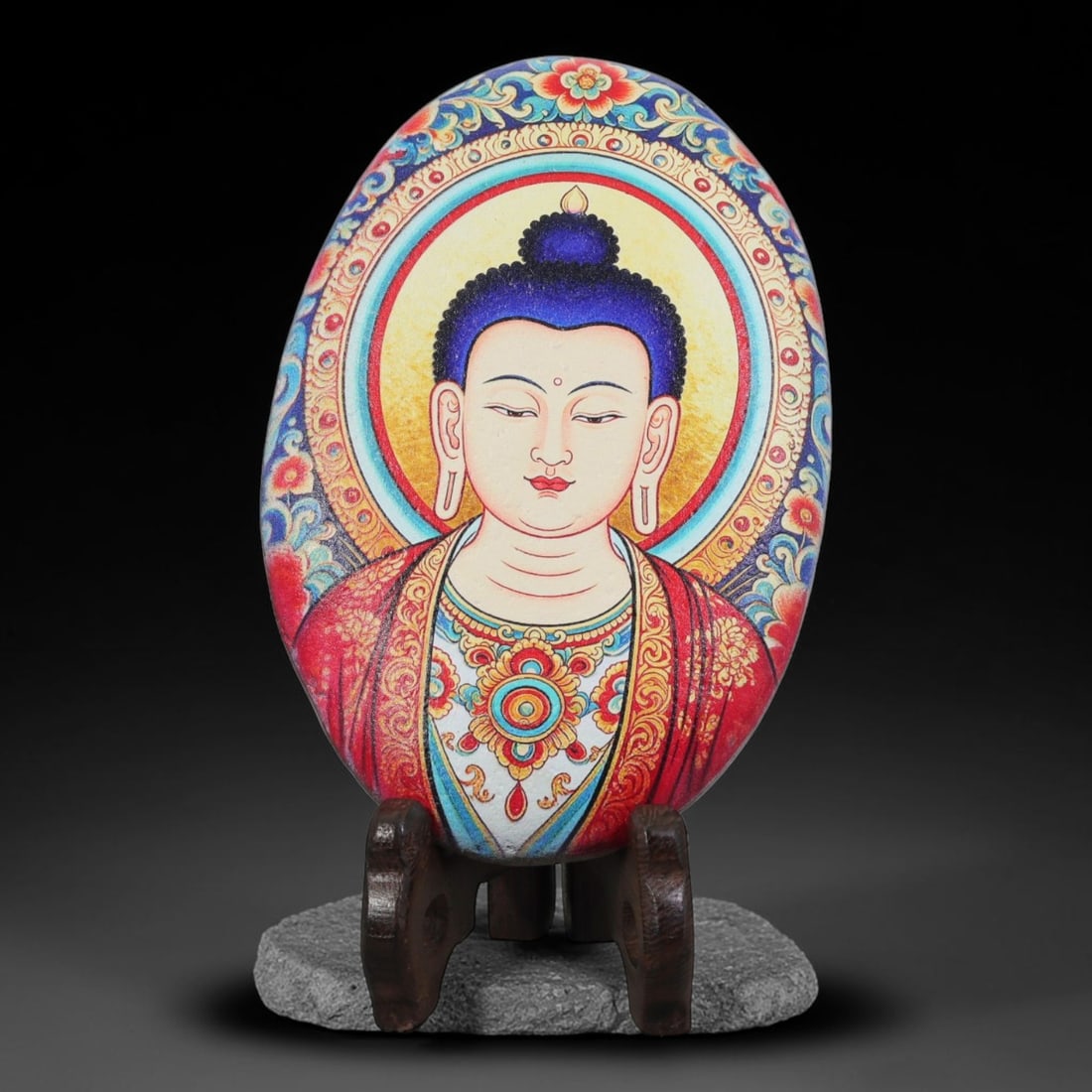 A Tibetan Thangka Style Painted River Stone with a Buddhist Figure, 72BC: Painted on a naturally rounded river stone, the work depicts a half-length Buddhist figure in a thangka-style composition. The figure is shown with a serene countenance and downcast eyes, a dark blue 