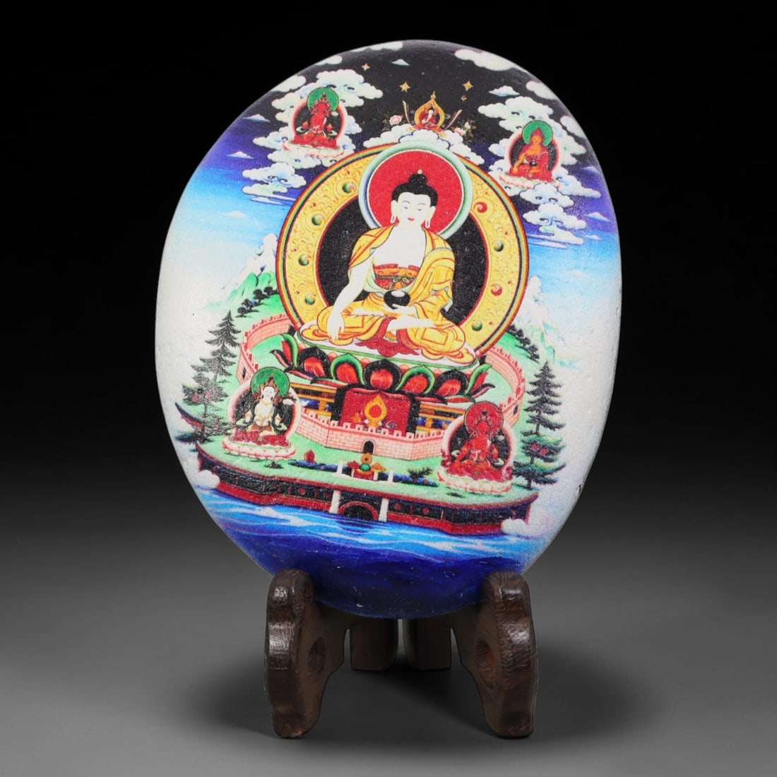 A Tibetan Thangka Style Painted River Stone with a Buddhist Figure, 76BC: Painted on a naturally rounded river stone, the work depicts a seated Buddhist figure in a thangka-style composition. The central figure is shown in a meditative posture wearing a yellow monastic robe