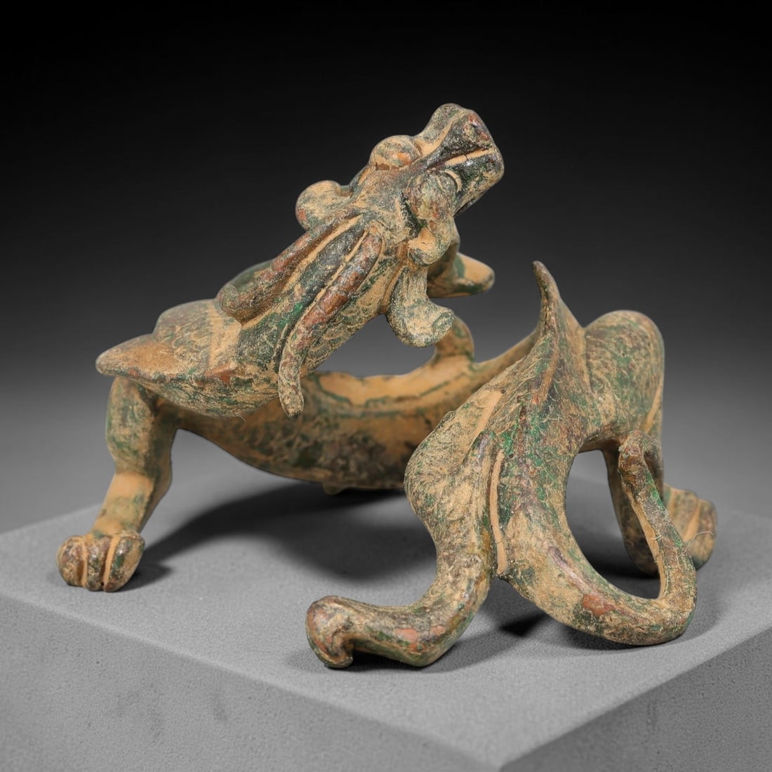A Chinese Bronze Mythical Qilin Beast Effigy, 68AD: Cast in bronze, this dynamically modelled mythical beast effigy is captured in a coiled, striding pose with head tilted upward. Fine detailing defines the facial features, elongated cranial appendages