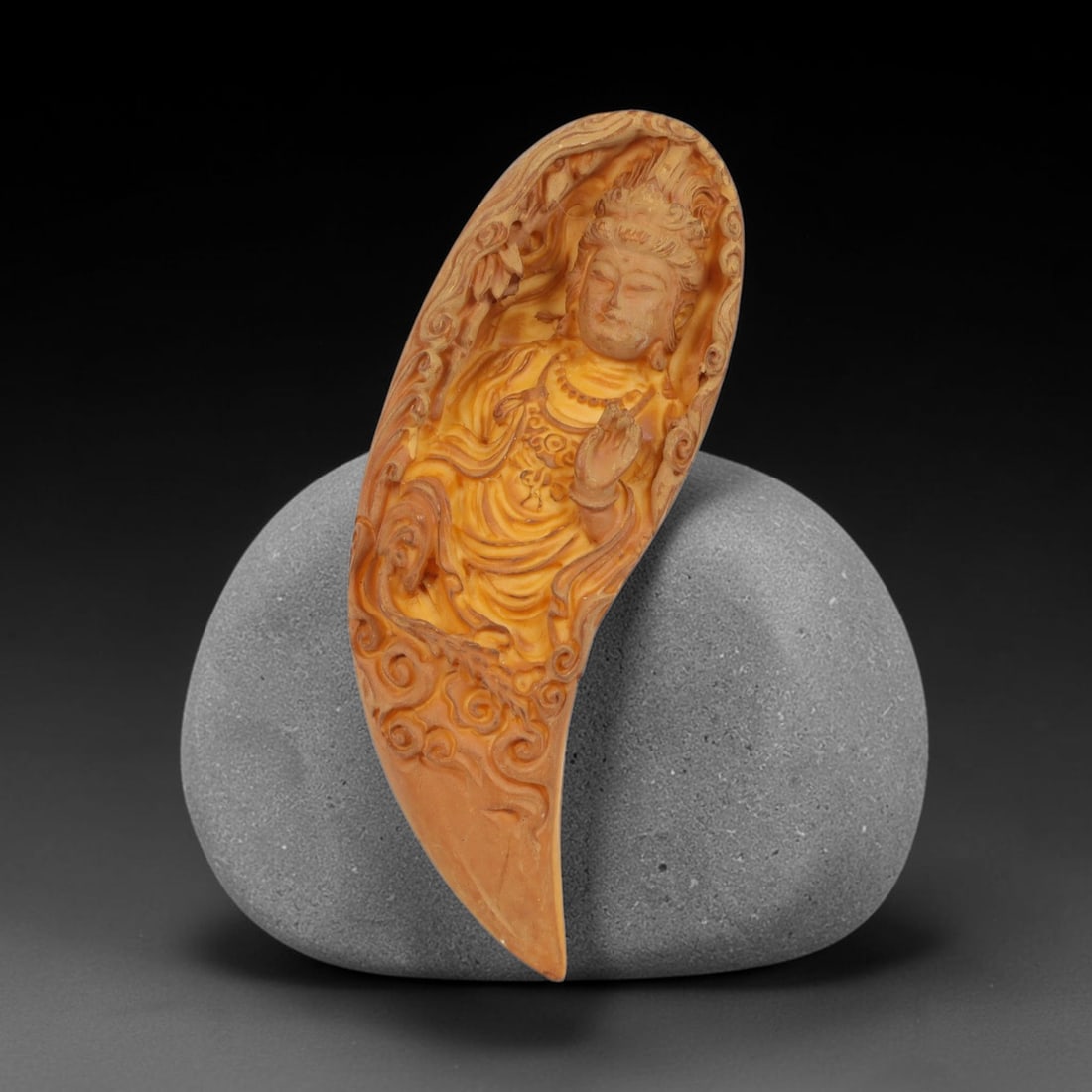 A Chinese Guanyin Deity Carved Tagua Nut Pendant Amulet, 11AD: Carved from tagua nut, this curved talon-shaped amulet features recessed relief carving enclosing the figure of Guanyin. The Bodhisattva is depicted with an ornate headdress, closed eyes, and serene f